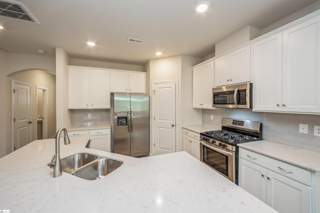 kitchen with backsplash, stainless steel appliances, sink, and white cabinetry