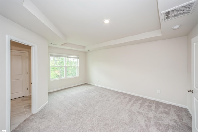 carpeted spare room featuring a raised ceiling