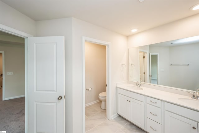 bathroom with double sink vanity, toilet, and tile patterned floors