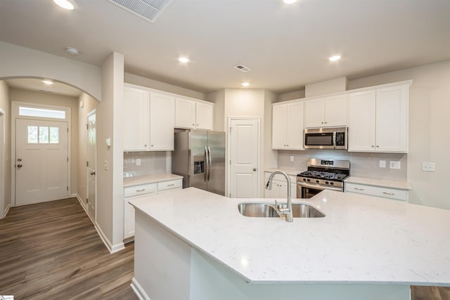 kitchen with appliances with stainless steel finishes, white cabinetry, backsplash, wood-type flooring, and sink