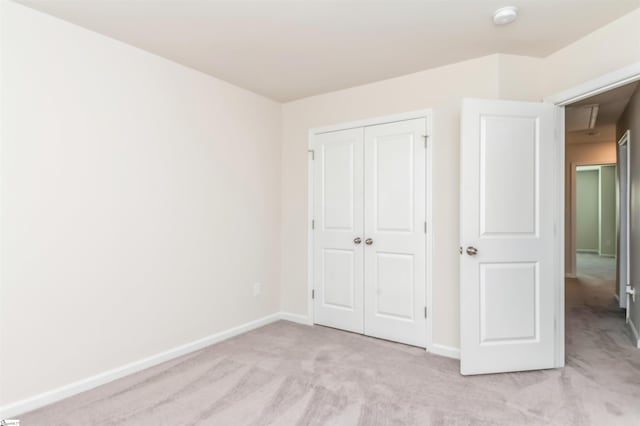 unfurnished bedroom featuring light colored carpet and a closet