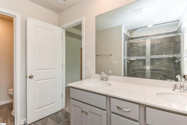 bathroom with a shower with shower door, double sink vanity, toilet, and tile patterned flooring