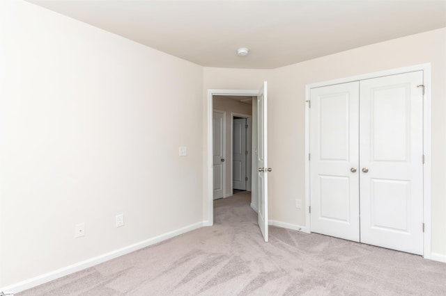 unfurnished bedroom with light carpet and a closet