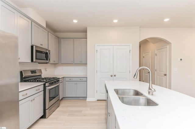 kitchen with stainless steel appliances, gray cabinets, light hardwood / wood-style floors, tasteful backsplash, and sink