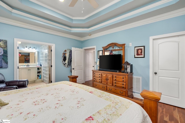 bedroom featuring connected bathroom, sink, ornamental molding, a raised ceiling, and light hardwood / wood-style floors