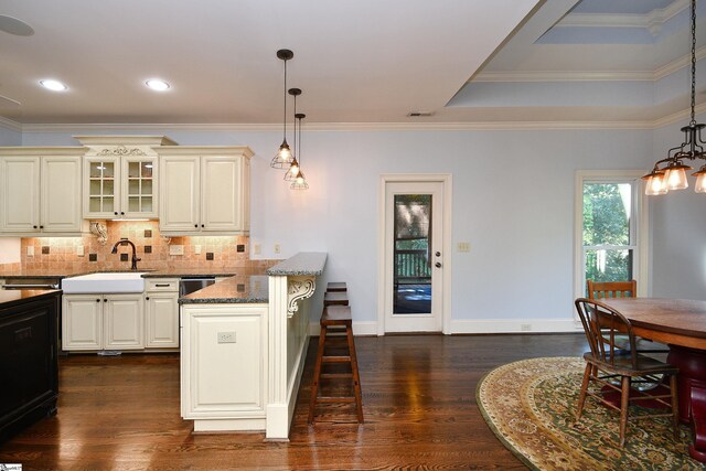 kitchen with dark hardwood / wood-style floors, dark stone counters, decorative backsplash, a kitchen bar, and decorative light fixtures