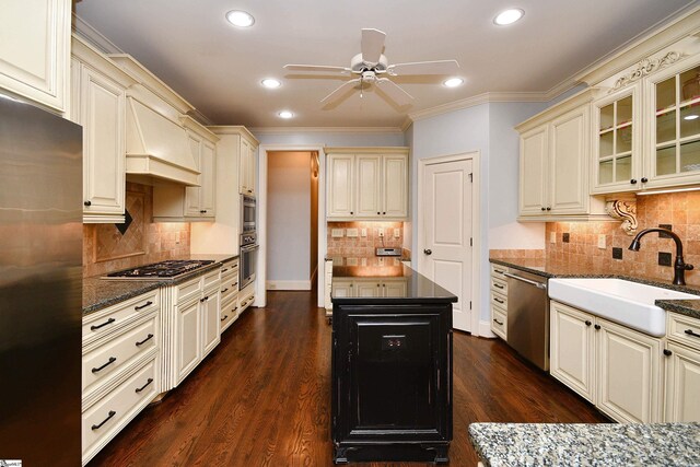 kitchen with decorative backsplash, ceiling fan, appliances with stainless steel finishes, dark wood-type flooring, and ornamental molding