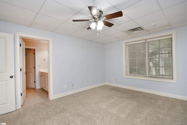 unfurnished bedroom featuring ceiling fan, light tile patterned floors, a drop ceiling, and ensuite bathroom