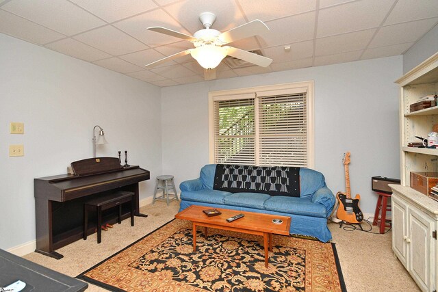 living room featuring a paneled ceiling, light colored carpet, and ceiling fan