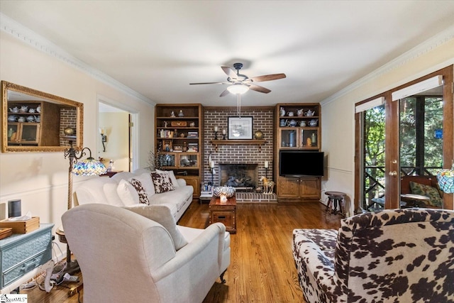 living room with a fireplace, wood-type flooring, ornamental molding, and ceiling fan