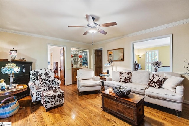 living room with ornamental molding, ceiling fan, and light hardwood / wood-style floors