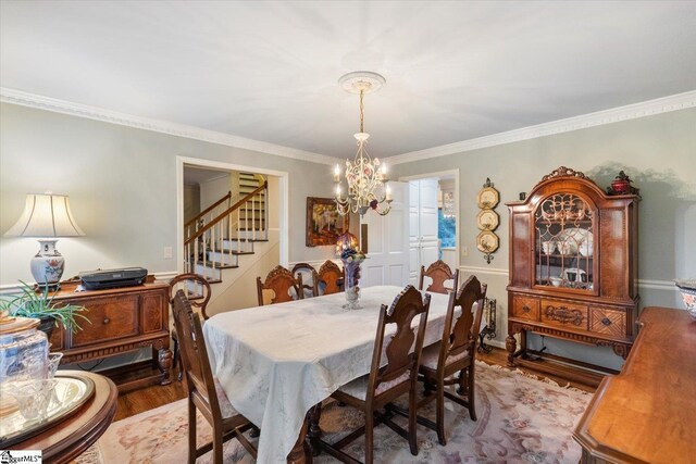 dining space featuring crown molding, light hardwood / wood-style flooring, and a notable chandelier