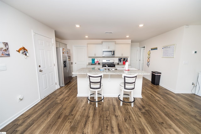 kitchen featuring white cabinetry, appliances with stainless steel finishes, a kitchen island with sink, and light stone counters