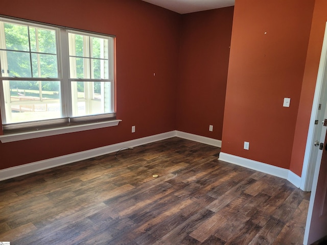 unfurnished room with dark wood finished floors and baseboards