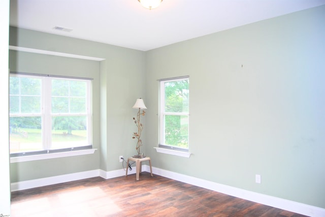 unfurnished room featuring visible vents, baseboards, and dark wood-style flooring