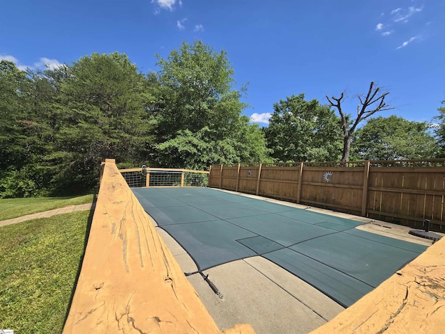 view of swimming pool with a yard and fence