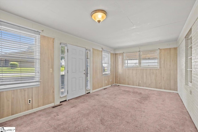 carpeted entrance foyer featuring crown molding and wooden walls