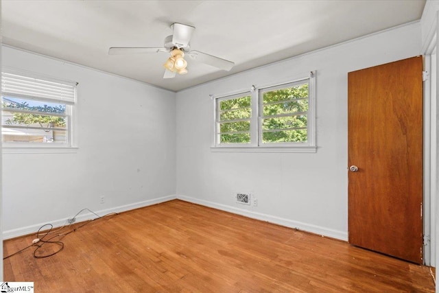 spare room featuring a ceiling fan, a healthy amount of sunlight, baseboards, and wood finished floors