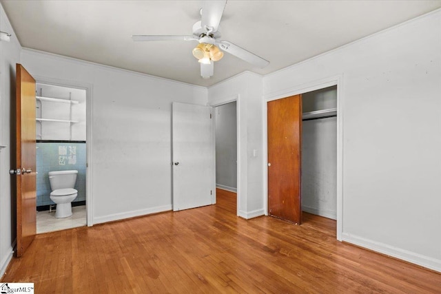 unfurnished bedroom with a closet, a ceiling fan, wood finished floors, and ensuite bathroom