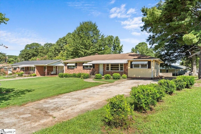 single story home featuring driveway, brick siding, and a front yard