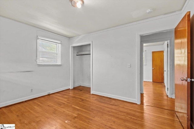 unfurnished bedroom with ornamental molding, a closet, baseboards, and light wood finished floors