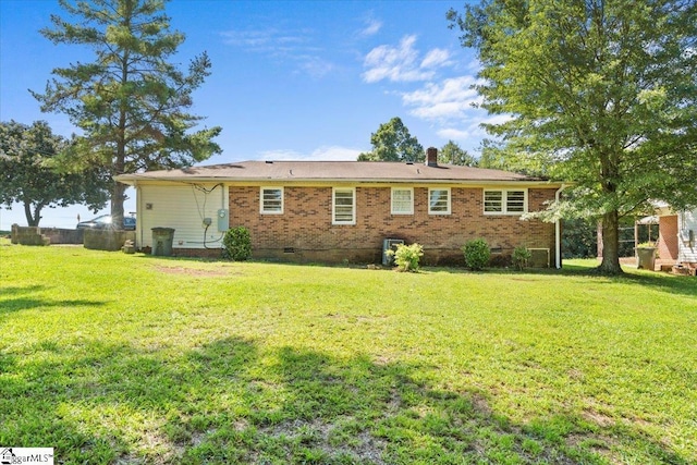 rear view of property featuring crawl space, brick siding, and a lawn