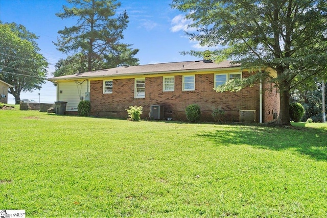 back of property with crawl space, central AC unit, a lawn, and brick siding