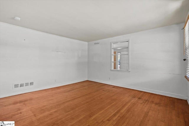 spare room with visible vents, baseboards, and wood finished floors