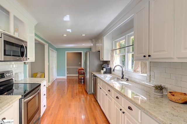 kitchen with sink, stainless steel appliances, white cabinets, and light stone counters