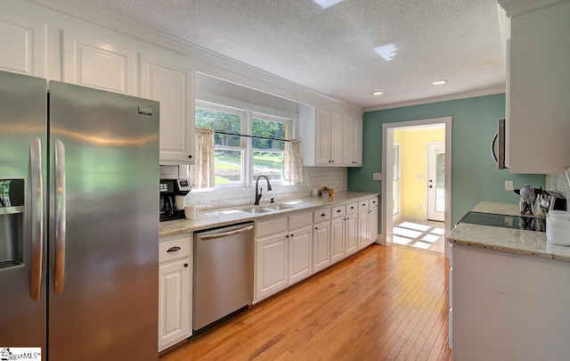 kitchen featuring appliances with stainless steel finishes, white cabinetry, ornamental molding, and sink