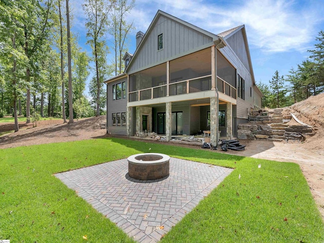 back of property with a patio area, a sunroom, a fire pit, and a yard