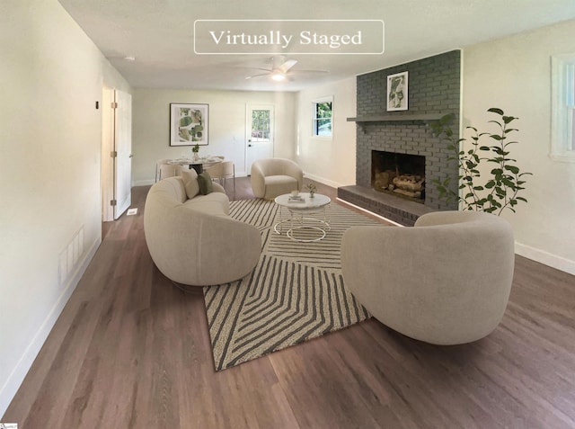 living area with a fireplace, visible vents, a ceiling fan, wood finished floors, and baseboards