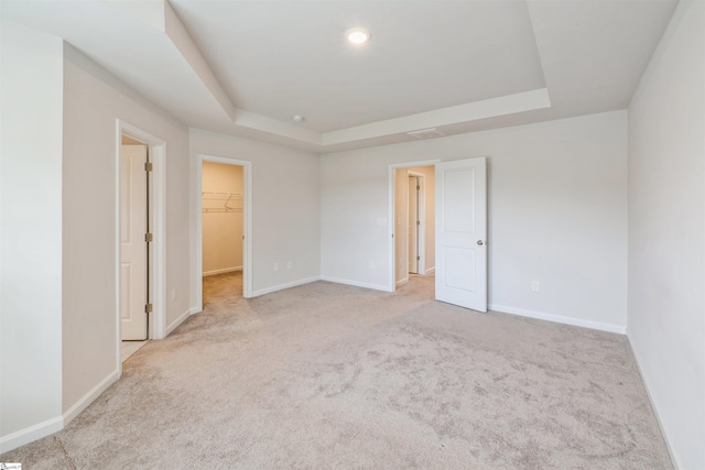 carpeted spare room with a raised ceiling