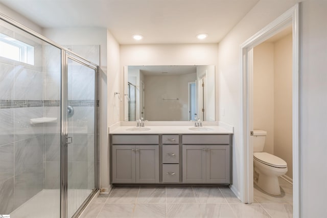 bathroom with tile patterned floors, double vanity, a shower with shower door, and toilet