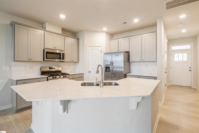 kitchen featuring sink, backsplash, light hardwood / wood-style flooring, and appliances with stainless steel finishes