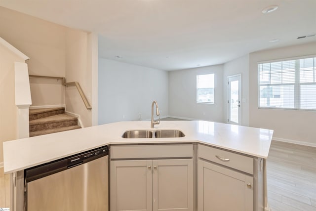 kitchen featuring sink, dishwasher, a kitchen island with sink, and light hardwood / wood-style floors