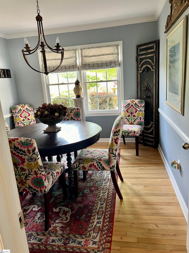 dining space with light hardwood / wood-style flooring, a notable chandelier, and crown molding