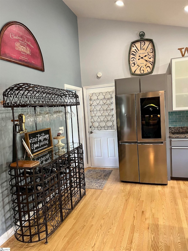 kitchen featuring light wood-type flooring, decorative backsplash, and stainless steel fridge