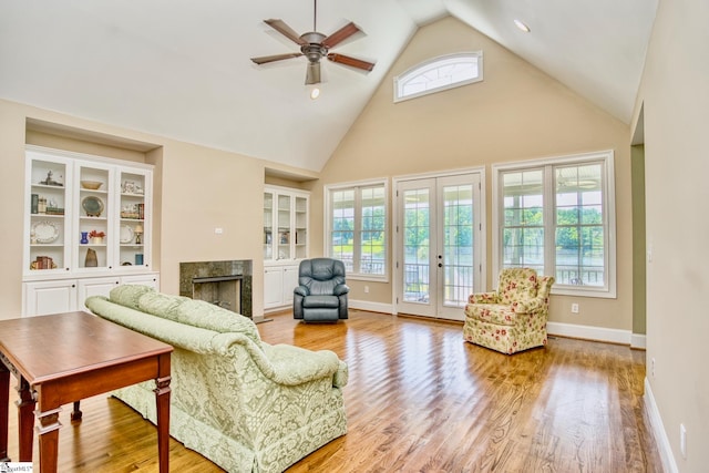 living room with ceiling fan, high vaulted ceiling, light hardwood / wood-style flooring, and a high end fireplace