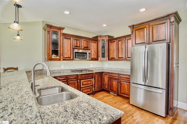 kitchen with appliances with stainless steel finishes, sink, light hardwood / wood-style flooring, and decorative light fixtures