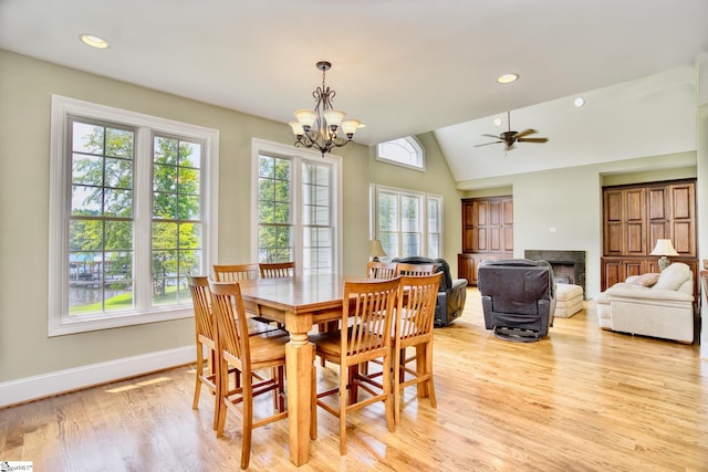 dining space with lofted ceiling, light wood-type flooring, and ceiling fan with notable chandelier