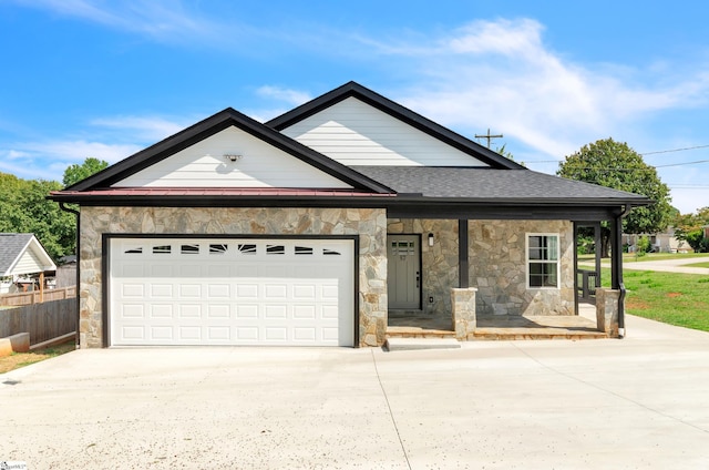 view of front facade featuring a garage, driveway, covered porch, and stone siding