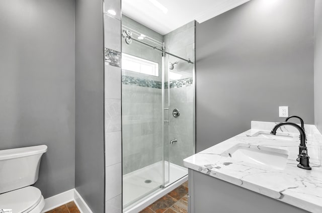 bathroom with toilet, baseboards, a sink, a stall shower, and double vanity