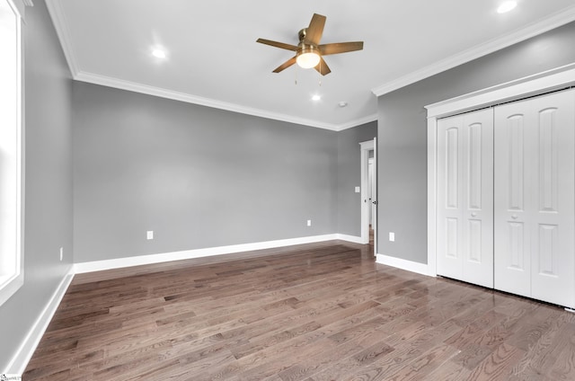 unfurnished bedroom with baseboards, ornamental molding, wood finished floors, and a closet