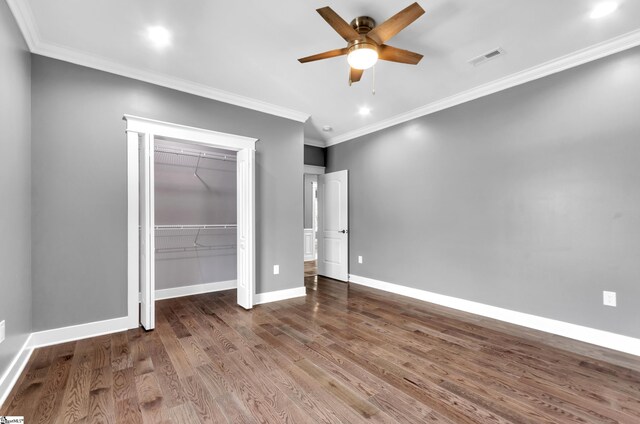 unfurnished bedroom featuring a closet, visible vents, crown molding, baseboards, and wood finished floors