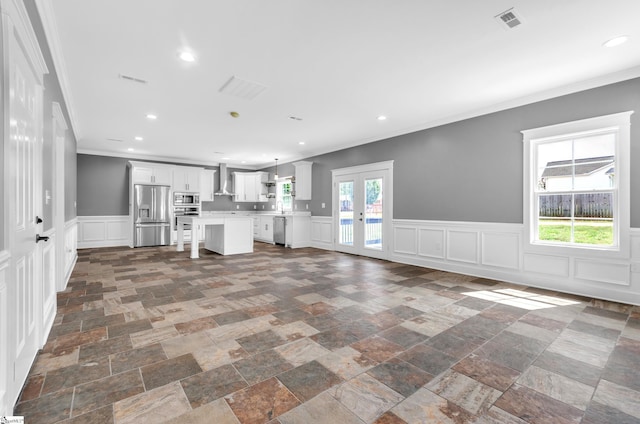 unfurnished living room with recessed lighting, visible vents, french doors, ornamental molding, and stone tile flooring