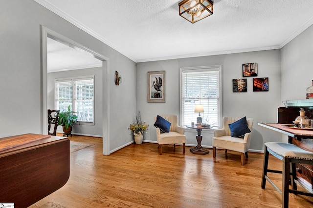 living area with ornamental molding, plenty of natural light, light hardwood / wood-style floors, and a textured ceiling