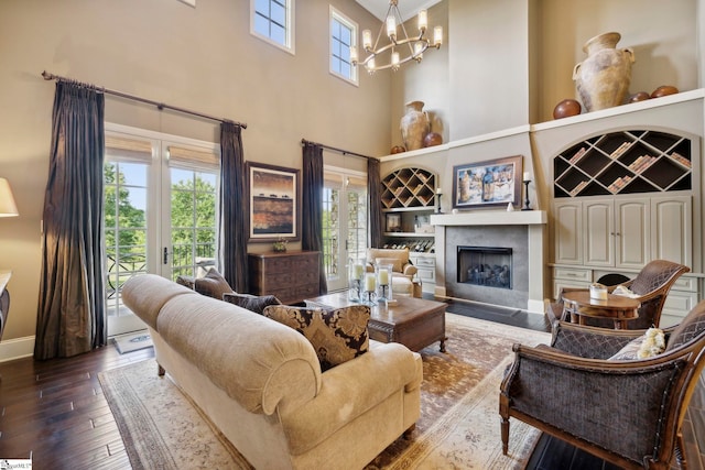 living room featuring a notable chandelier, a high ceiling, hardwood / wood-style floors, and a high end fireplace