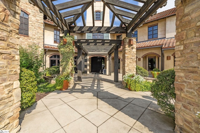 property entrance with a pergola and a patio area