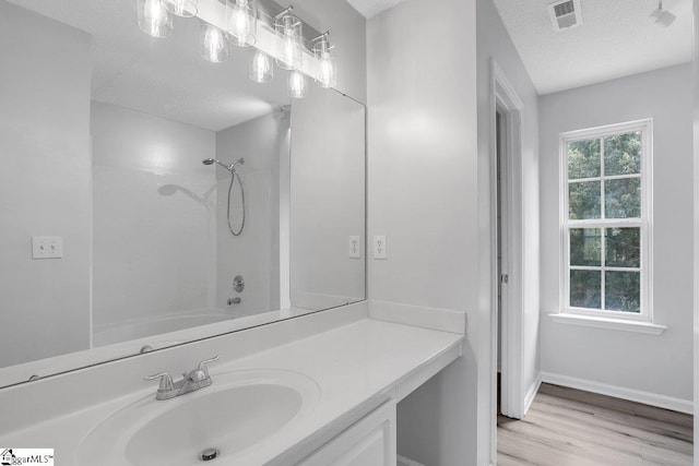 bathroom featuring hardwood / wood-style floors, vanity, a textured ceiling, and shower / washtub combination